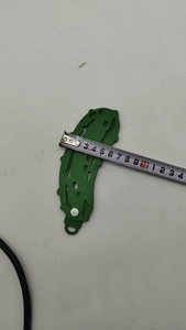Macro view of 4cm wide green wooden Christmas pickle ornament showing measurement scale