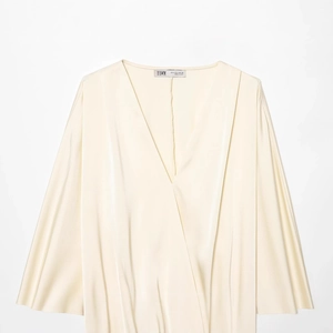 Blouse élégante en satin ivoire avec décolleté en V profond et texture soyeuse