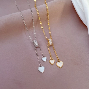 Macro detail of gold and silver heart necklaces with shell inlay on soft silk fabric