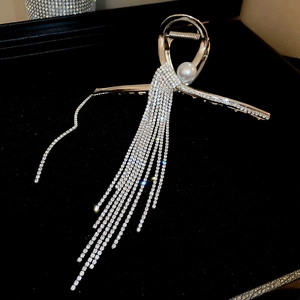 Détail de pince à cheveux argentée avec perle et longues chaînes à glands en strass