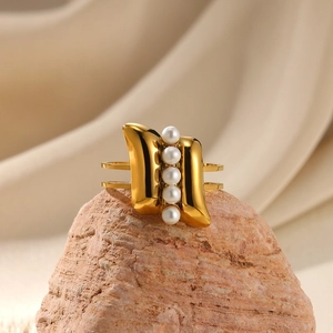 Macro detail of golden double-band open ring with five white pearls on natural stone