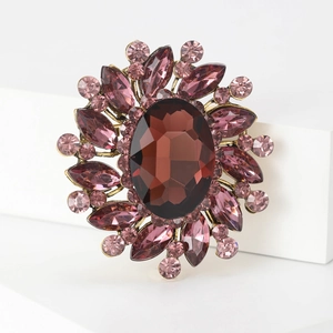 Macro detail of a vintage flower brooch with brown oval gem and pink crystals