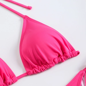 Detail of a bright pink halter bikini top featuring pleated cups and slim neck ties