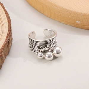 Retro silver wide textured open ring with bell pendants on minimalist wooden background