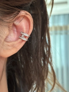 Close-up of silver letter H ear cuff with cubic zirconia worn on human ear