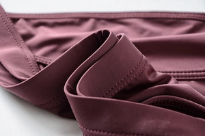 Close-up of seamless stitching and breathable ice silk fabric on dark purple underwear