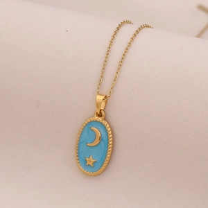 Detailed shot of golden moon and star pendant with blue enamel on a soft fabric background