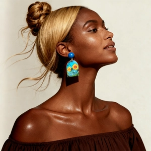Close-up of model wearing sunflower pattern arch earrings with blue bead stud detail