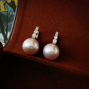 Détail macro de boucles d'oreilles en perles dorées avec oxydes de zirconium brillants