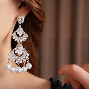 Close-up of fan-shaped tassel pearl earrings with sparkling rhinestones on model