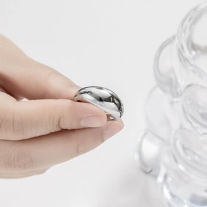 Detailed view of polished silver titanium dome ring held between fingers