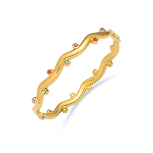 Minimalist gold wave titanium bangle with colorful embedded gemstones on white background