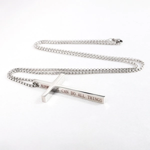 Macro detail of silver cross pendant with Philippians engraving on bead chain necklace