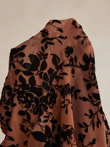 Détail du tissu en maille transparente avec motifs floraux floqués en velours noir