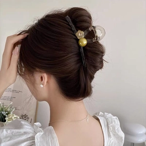 Detail of a large translucent grey hair claw clip with yellow bead and flower on long hair