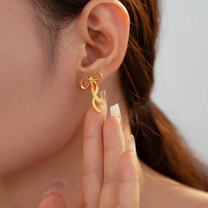 Schicke 18k vergoldete Titanstahl Schleifenohrstecker getragen von einem Modell