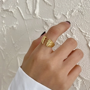 Detail view of gold adjustable ring with unique molten lava texture on model hand