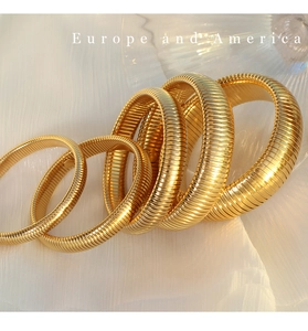 Macro detail of four gold-plated snake bone bracelets with elegant spiral texture