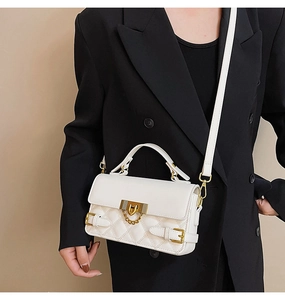 Close-up of a white quilted crossbody bag featuring gold metal buckles and chain strap