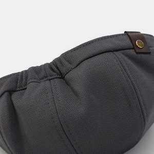 Detail of dark grey knit newsboy cap featuring brown leather strap and metal STYLE button