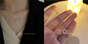 Close-up of gold layered necklace featuring dual H-letter pendants and polished finish