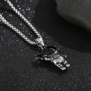Gros plan détaillé du pendentif astronaute avec étoile noire sur chaîne maille miroir