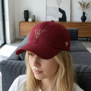 Cappellino da baseball bordeaux classico con logo ricamato in oro in un ambiente moderno