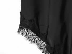 Detail of silk dress showing black lace trim and smooth fabric texture close-up