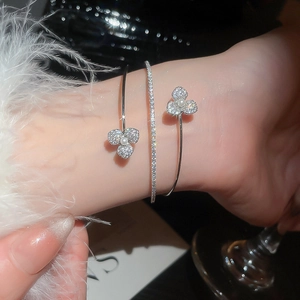 Detail shot of a layered pearl flower bangle and zircon bracelet on woman's wrist