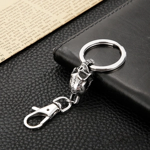 Close-up of vintage silver skull keychain with lobster clasp on black leather