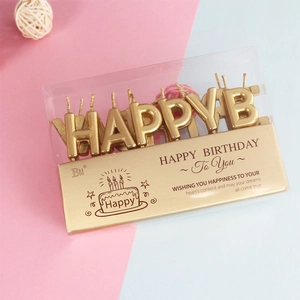 Macro shot of gold Happy Birthday letter candles in a transparent gift box set