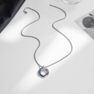 Detail of interlocking triple ring pendant in silver and blue on a sleek metal chain