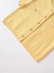 Detailed macro view of cream yellow ribbed knit cardigan with golden dome buttons