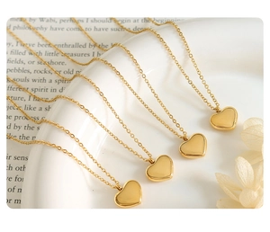 Close-up of heart-shaped gold pendants with polished mirror finish on white ceramic edge