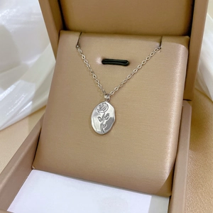 Detailed macro view of an oval rose relief pendant on a silver titanium steel necklace