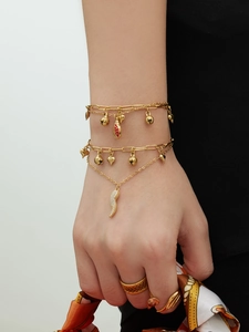 Gros plan d'un bracelet doré multicouche avec breloques cœur, cloche et fraise sur mannequin