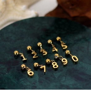 Detailed top view of gold numbered pendants 0-9 for DIY jewelry making on green base