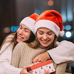 Luminous plush red and white Christmas hats worn by smiling women with holiday gift box