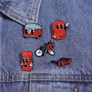 Detailed close-up of five red cartoon enamel pins pinned onto a blue denim jacket pocket