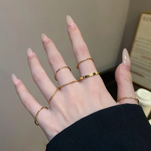 Close-up of minimalist gold ring set featuring textured bands and stackable rings on hand