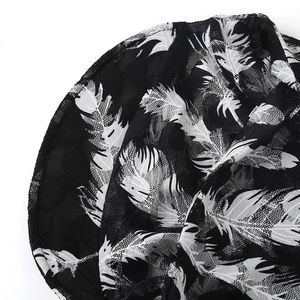 Close-up of black lace fabric featuring white feather patterns and breathable mesh texture