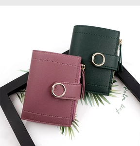 Detail of short leather wallets in dark green and pink with metal ring closure and litchi texture