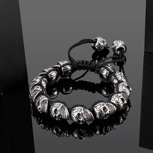 Detailed close-up of punk skull beads on black braided rope bracelet with reflections