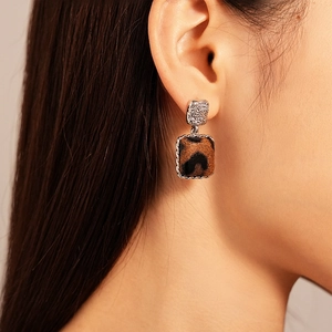 Close-up of leopard print square earrings with sparkling diamond stud on female model