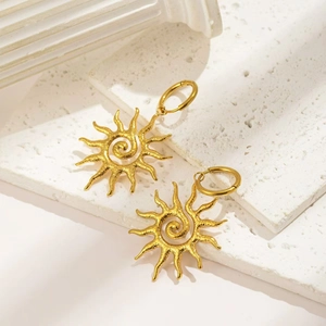 Golden sun earrings with spiral center and flame rays on white textured stone