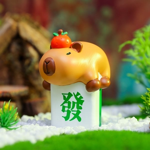 Macro detail of Capybara resin figurine with orange on white Mahjong tile in moss decor