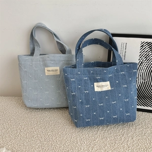 Vue détaillée des sacs cabas en denim bleu clair et foncé avec broderie de nœuds blancs