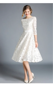 Close-up of intricate floral lace embroidery and sheer mesh texture on white dress