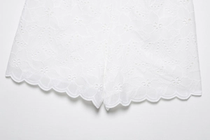 Dettaglio dei pantaloncini in pizzo bianco con ricami traforati e bordo ondulato
