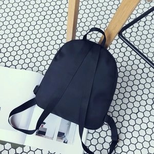 Minimalist black small backpack in nylon fabric shown from top view on home tile floor